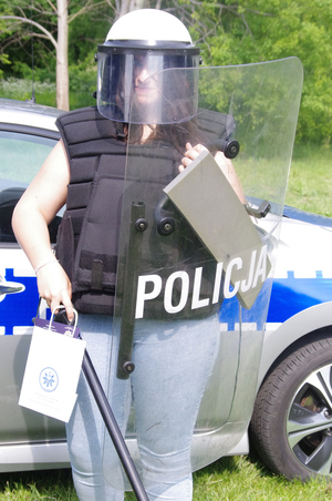 kobieta w policyjnym stroju do zadań specjalnych w tle radiowóz