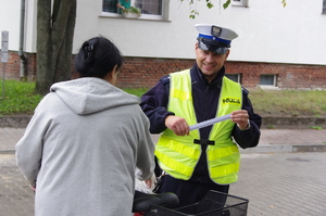 policjanci rozmawiają z rowerzystami w tle ulica i zabudowania