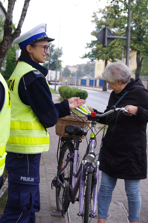 policjanci rozmawiają z rowerzystami w tle ulica i zabudowania