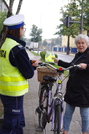 policjanci rozmawiają z rowerzystami w tle ulica i zabudowania