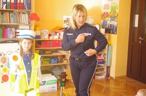 policjantka rozmawia z przedszkolakami, w tle dzieci i sala