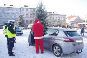 Mikołaj i policjanci dla kierowców w tle zabudowania i ulica