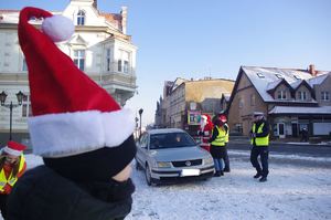 Mikołaj i policjanci dla kierowców w tle zabudowania i ulica