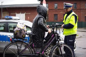 policjant kontroluje rowerzystę w tle ruch uliczny