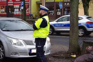policjant kontroluje pojazd w tle ruch uliczny