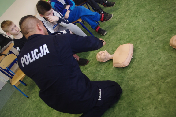 Policjanci dzielnicowi uczą dzieci pierwszej pomocy w tle klasa lekcyjna