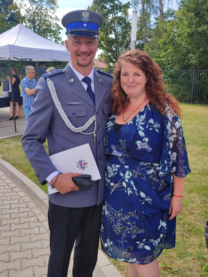 policjant umundurowany  z żoną w tle jednostka