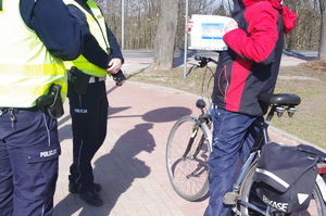 policjanci rozmawiają z rowerzystą w tle droga