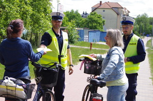policjanci i rowerzyści w tle ulica i zabudowania