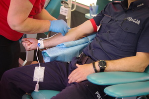 policjanci i inne osoby oddają krew w tle ambulans