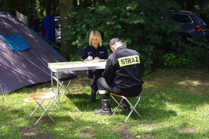 policjantka i strażak przy stoliku wypełniają dokumenty w tle las