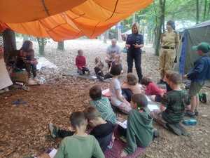 policjantka i strażaczka rozmawiają z zuchami  w tle las