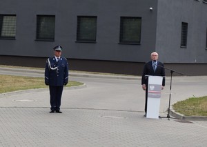 przemowa przy mównicy w tle budynke komendy