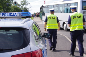 policjanci w tle idące dzieci obok radiowóz i autobus szkolny