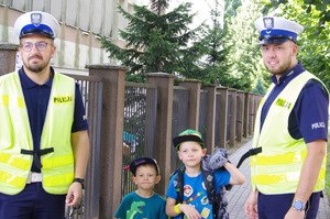 policjanci, obok nich dwójka dzieci w tle zabudowania