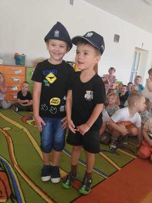 dwóch chłopców w policyjnych czapkach w tle sala