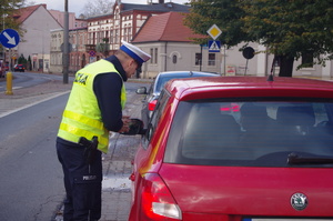 policjant kontroluje kierowcę w tle ulica i zabudowania