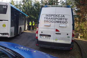 funkcjonariusze sprawdzają pojazd w tle radiowóz policyjny i ulica