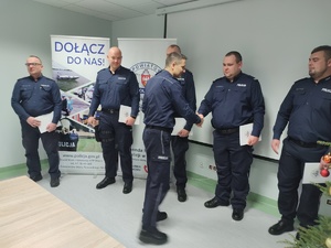 komendant wręcza wyróżnienia w tle ściana i choinka