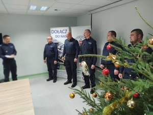 komendant wręcza wyróżnienia w tle ściana i choinka