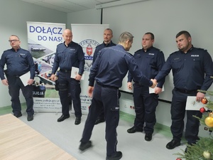 komendant wręcza wyróżnienia w tle ściana i choinka