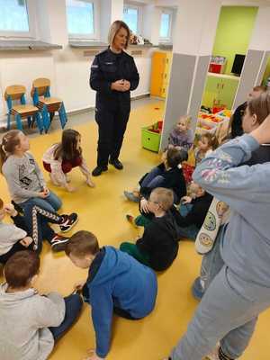 policjantka rozmawia z dziećmi w tle okna w sali