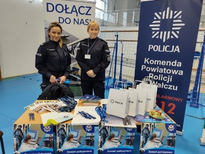 dwie policjantki w tle banery promujące zawód policjanta
