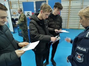 policjantki rozmawiają z odwiedzającymi targi  w tle wnętrze hali sportowej i inni wystawcy