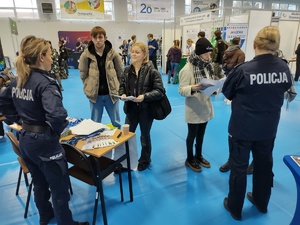policjantki rozmawiają z odwiedzającymi targi  w tle wnętrze hali sportowej i inni wystawcy