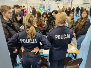 policjantki rozmawiają z odwiedzającymi targi  w tle banery promujące policję