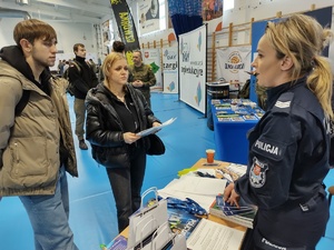 policjantki rozmawiają z odwiedzającymi targi  w tle banery promujące policję