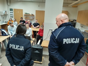 policjanci w tle sala i uczestnicy spotkania