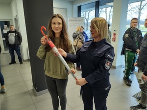 policjantka wręcza kobiecie parasol w tle hol komendy