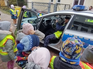 dzieci oglądają radiowóz policyjny w tle zabudowania