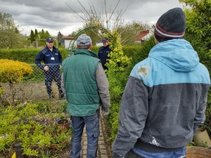 policjanci rozmawiają z działkowcami w tle roślinność
