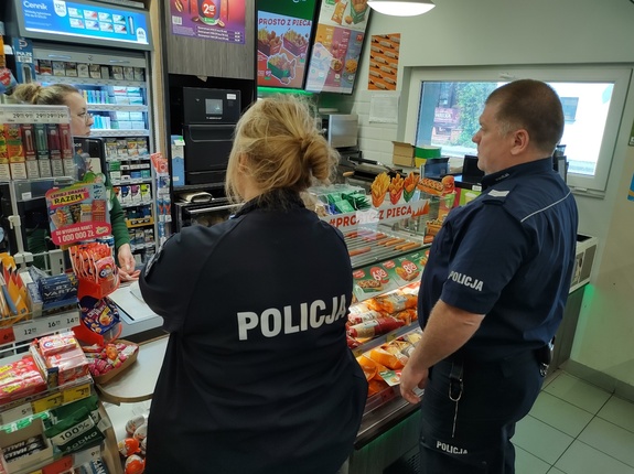 policjant i policjantka w sklepie w tle za ladą sprzedawca