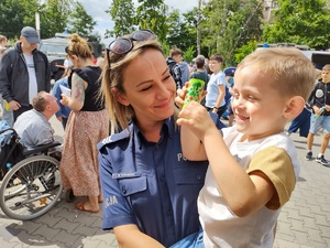 dzieci bawią się na festynie u policjantów w tle uczestnicy festynu, radiowozy i inne służby