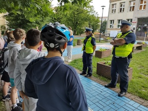 policjanci oceniają egzamin uczniów w tle uczniowie i mini miasteczko RD