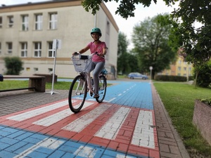 dziewczynka jedzie rowerem w tle szkoła