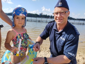 policjant rozmawia z dziećmi na kąpielisku w tle plaża