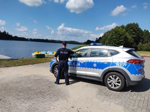 policjant przy radiowozie w tle jezioro