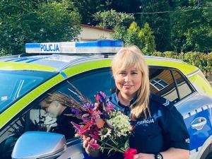 policjantka z bukietem kwiatów w tle radiowóz