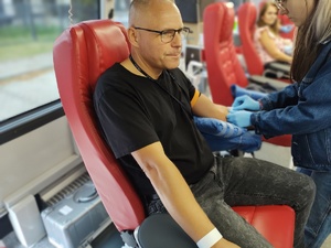 policjant w cywilnym ubraniu na fotelu oddaje krew w tle wyposażenie ambulansu, za oknem budynek
