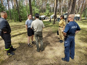 służby kontrolują obóz w tle las