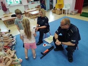 policjanci rozmawiają z dziećmi w tle sala
