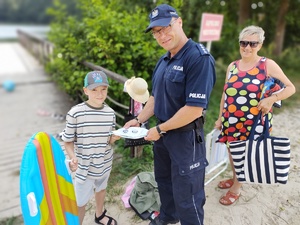 policjant rozmawia z plażowiczami w tle plaża