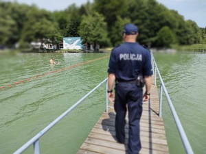 policjant idzie pomostem w tle jezioro