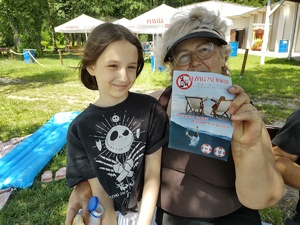 policjant rozmawia z plażowiczami w tle plaża