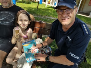 policjant rozmawia z plażowiczami w tle plaża