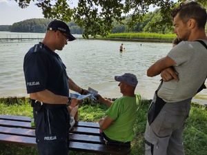 policjant rozmawia z plażowiczami w tle plaża